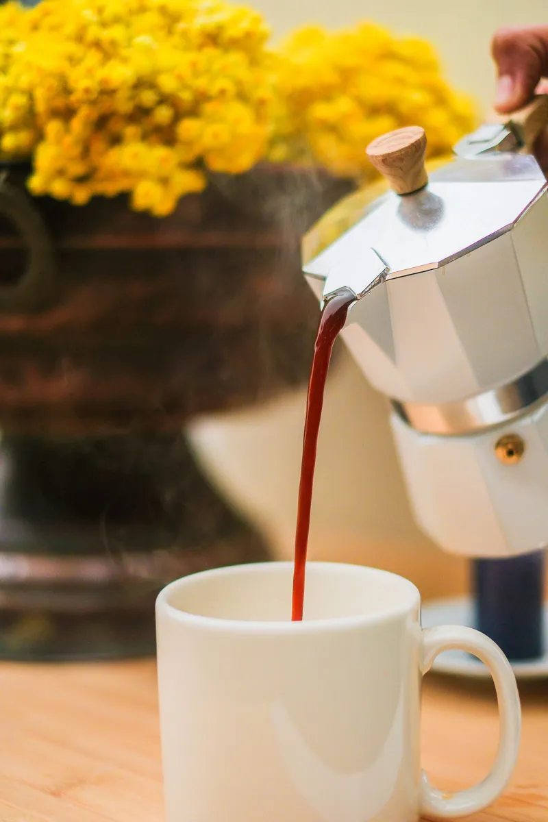 Cafetera italiana de acero inoxidable sirviendo el café en una taza