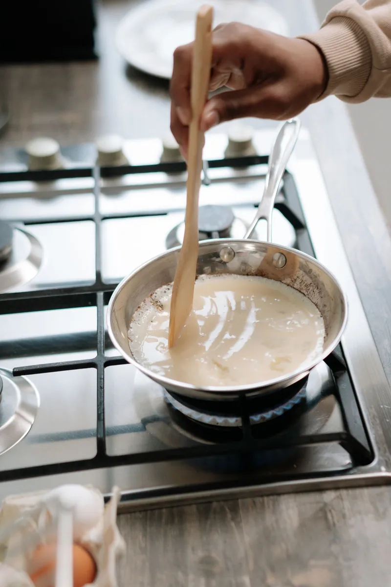 Removiendo una salsa en la sartén sobre el fuego de la cocina